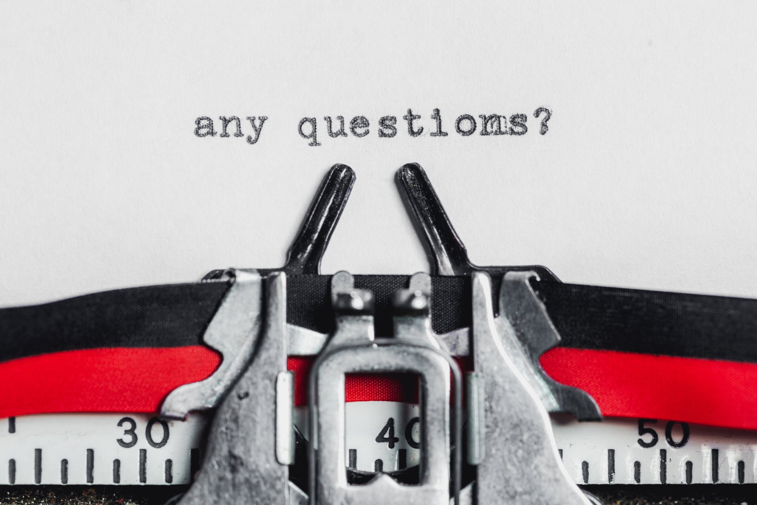 The words 'any questions' are displayed in the center of a page on a vintage typewriter. | Frequently asked questions page. | LunaSola Designs, LLC